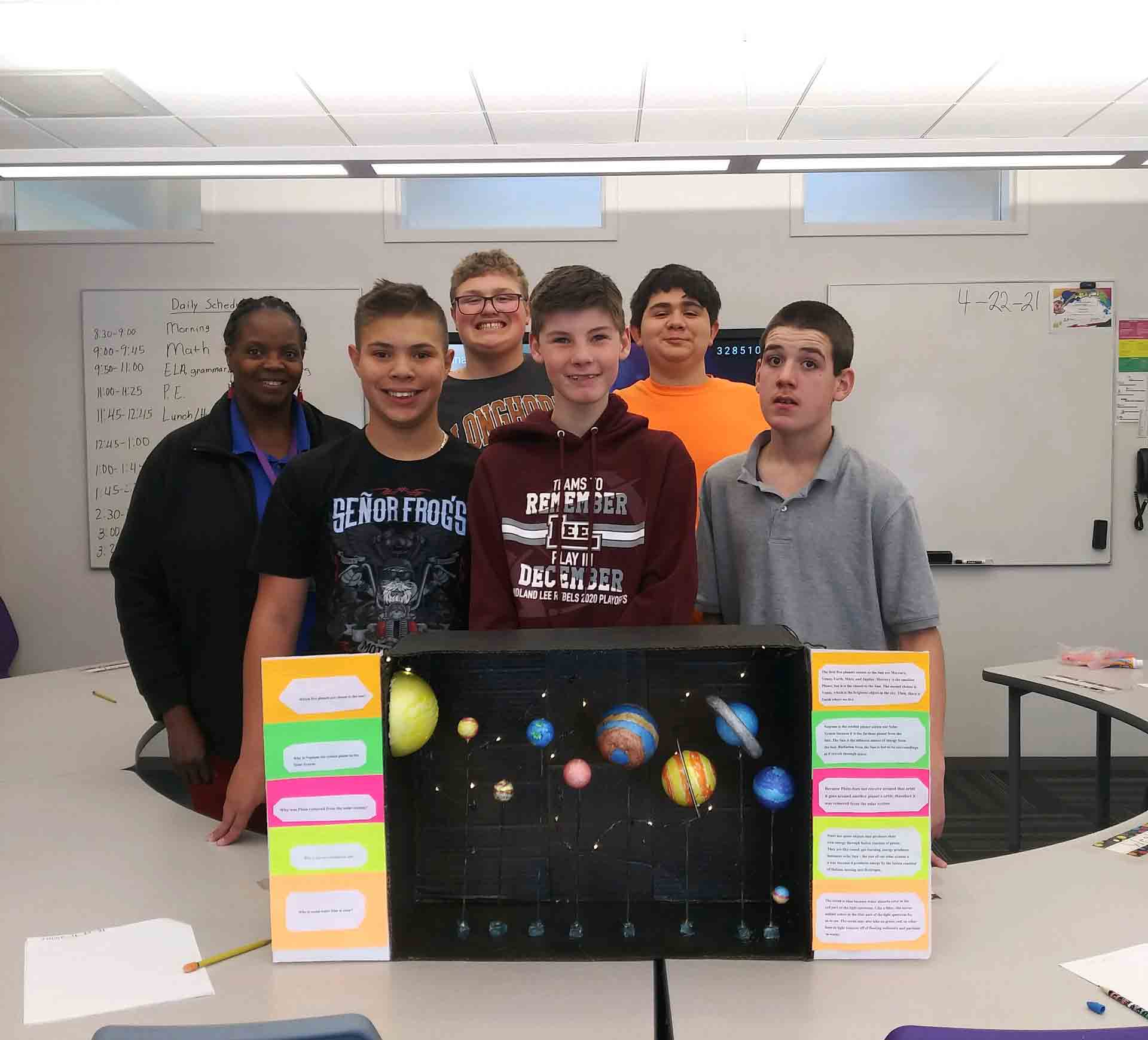 A group of science students standing behind their solar system project